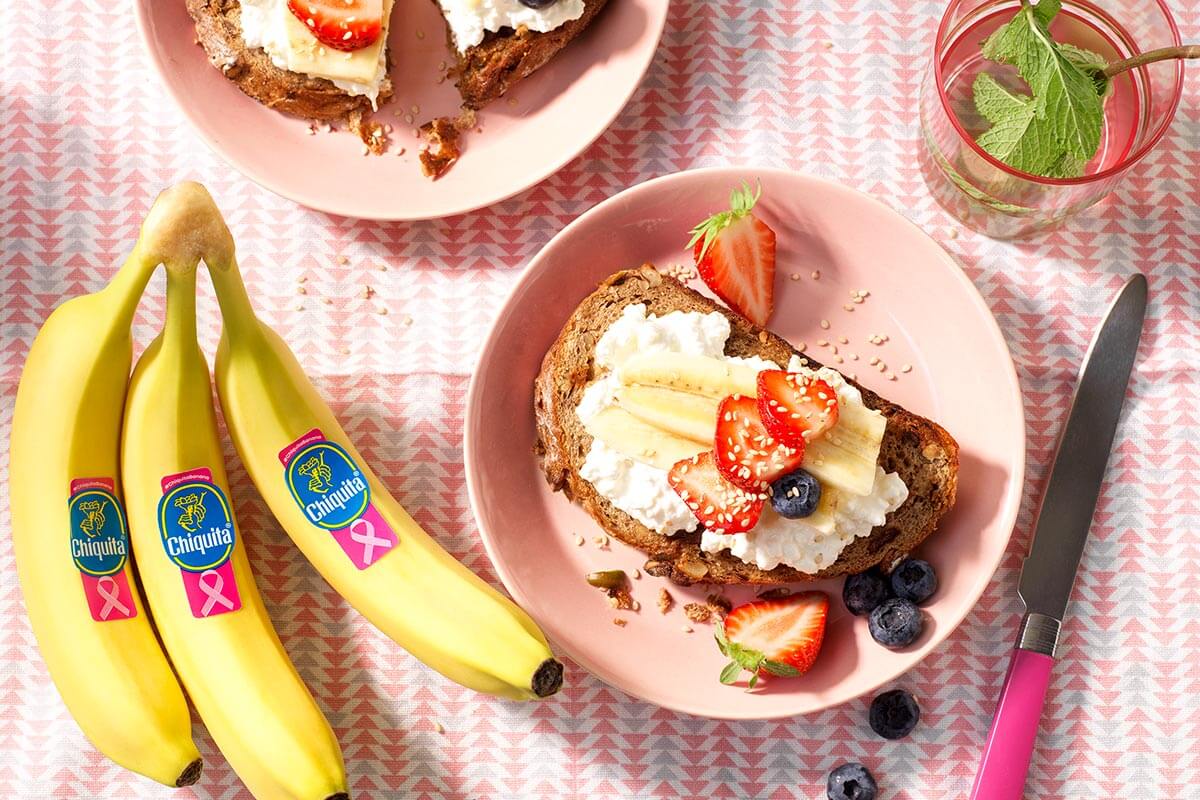 Vollkornbrot mit fettfreiem Hüttenkäse, Chiquita Bananen, Erdbeeren, Blaubeeren und Sesamsamen