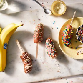 Gefrorene, mit Schokolade überzogene Bananen-Lollies mit (bunten) Streuseln