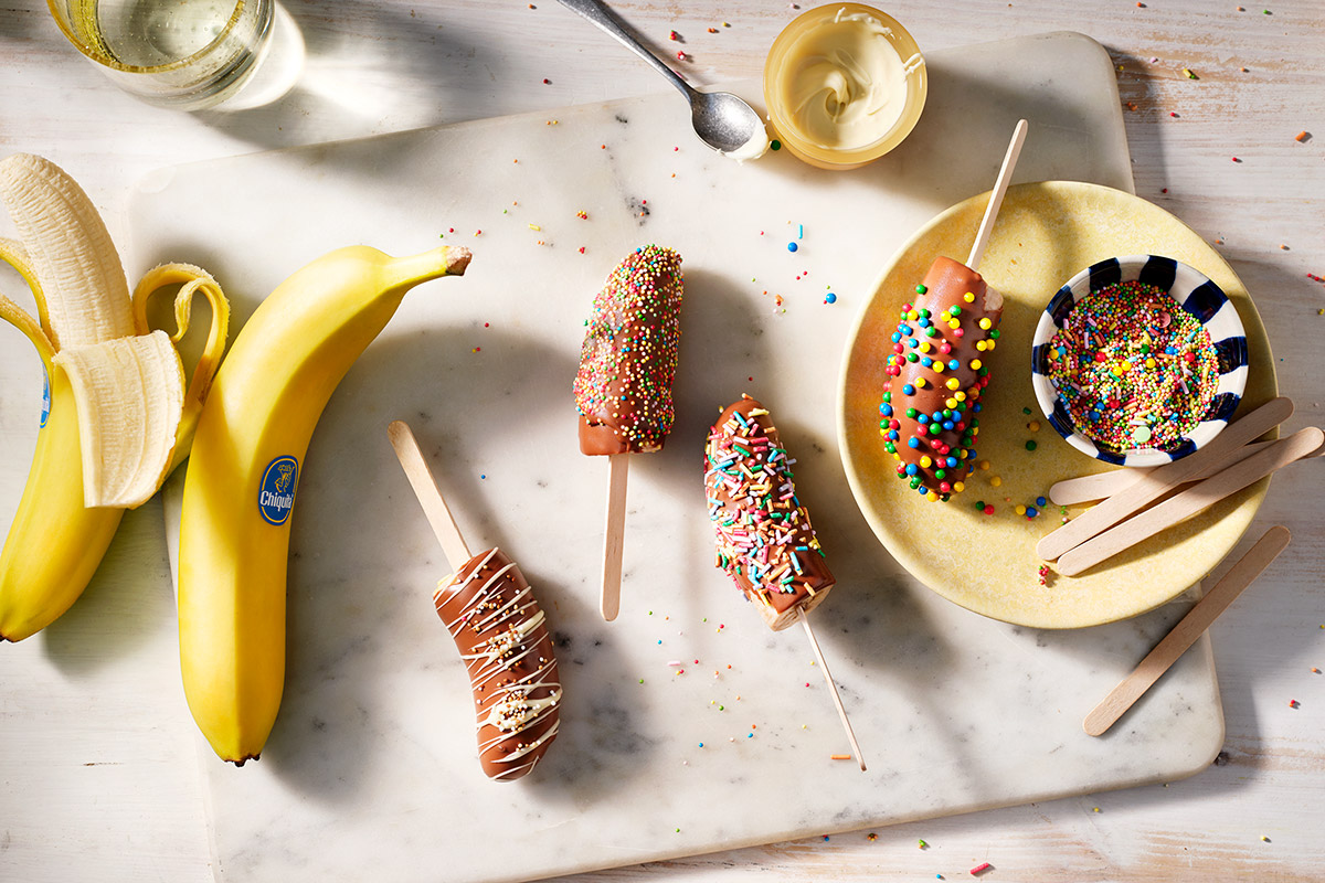 Gefrorene, mit Schokolade überzogene Bananen-Lollies mit (bunten) Streuseln